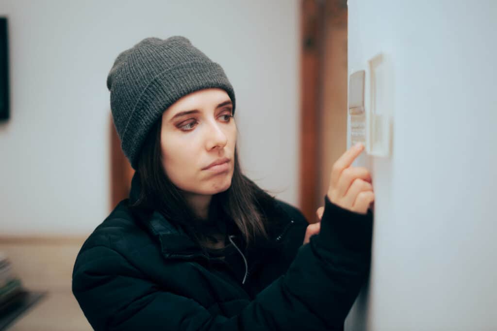 Cold woman adjusting thermostat